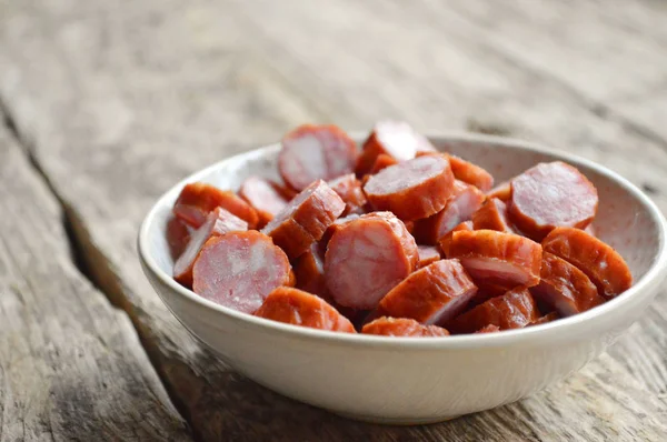 Smoked sausages in a plate on a wooden background. Food Photo — Stock Photo, Image