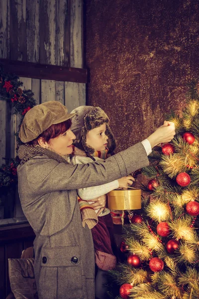 Mutter und Sohn schmücken einen Weihnachtsbaum. — Stockfoto