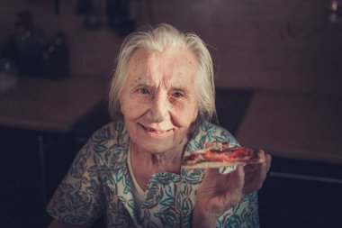 Çok yaşlı kadın evde bir parça pizza yemek.