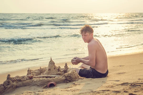 El hombre construye un castillo de arena en el océano . — Foto de Stock