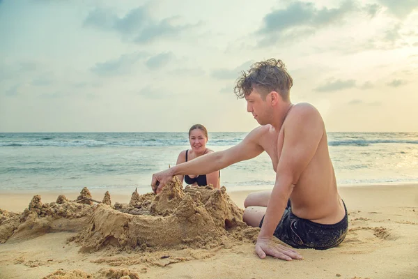 People build a castle of sand on the ocean.