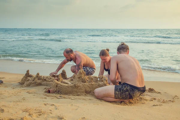 People build a castle of sand on the ocean.