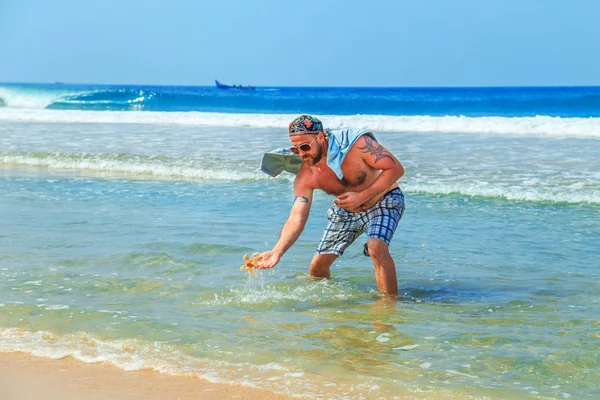 El hombre atrapa un cangrejo en la playa . — Foto de Stock