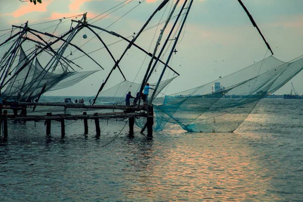 Vissers zijn het gooien van Chinese netten in Fort Kochi. — Stockfoto