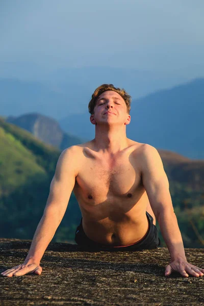 O homem está envolvido em exercícios físicos entre as montanhas . — Fotografia de Stock