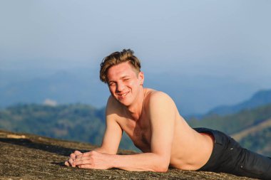 Atletik gülümseyen adam bir dağın tepesinde yer alır.. 