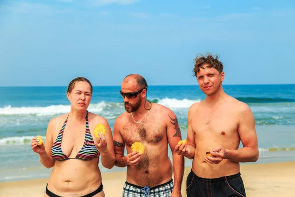 Dos hombres y una chica están comiendo piña. . — Foto de Stock