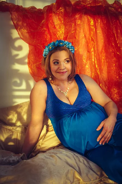 Mooie gelukkig zwangere vrouw in een blauwe jurk. — Stockfoto