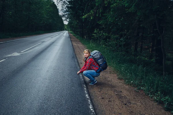 Μοναχικό κορίτσι ωτοστόπ στον δρόμο με ένα σακίδιο. — Φωτογραφία Αρχείου