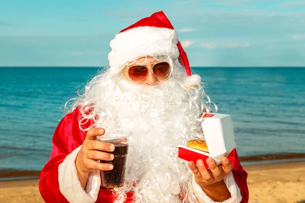 Noel Baba sahilde bir hamburger yemek. 