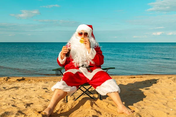 Noel Baba sahilde bir hamburger yemek. 