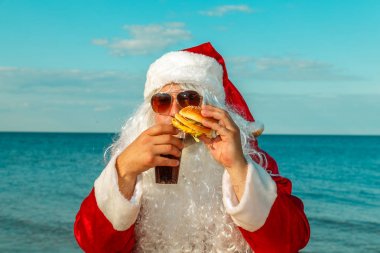 Noel Baba sahilde bir hamburger yemek. 