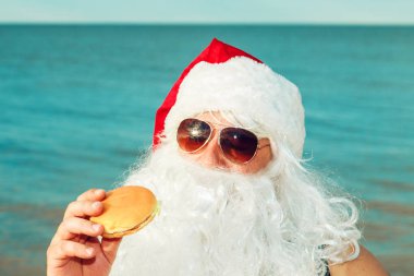 Noel Baba sahilde bir hamburger yemek. 
