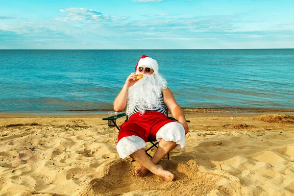 Santa Claus on the beach eating a hamburger. Stock Photo