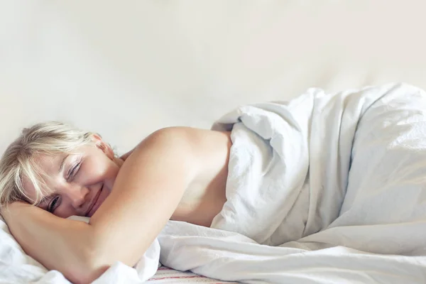 Hermosa chica rubia despierta en la cama . — Foto de Stock