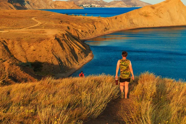 Two tourists walk across the hills.