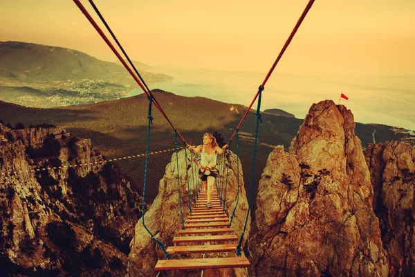 女性奈落の底に吊り橋を歩いています。. — ストック写真