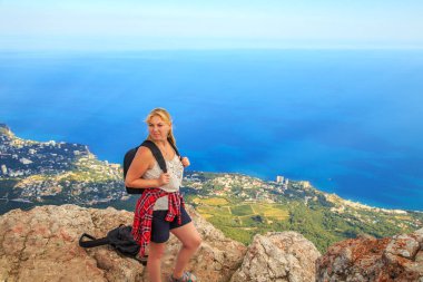 Bir dağın tepesinde bekleyen bir sırt çantası ile kız.