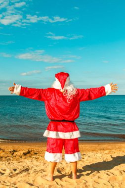 Noel Baba sahilde uzanmış silah ile duruyor. 