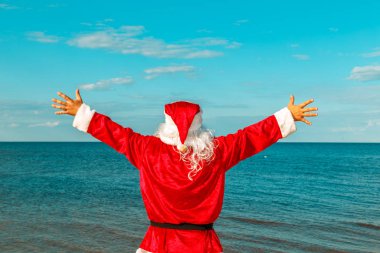 Noel Baba sahilde uzanmış silah ile duruyor. 