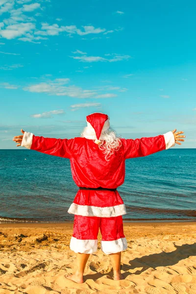 Noel Baba sahilde uzanmış silah ile duruyor. 