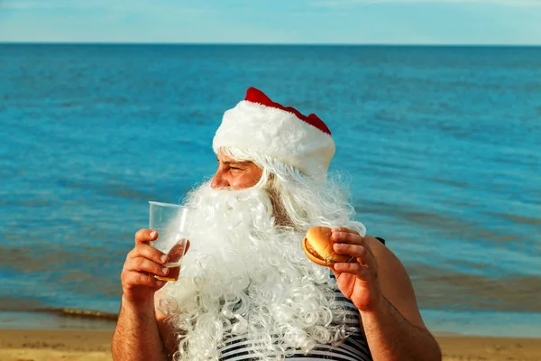 Noel Baba sahilde bir hamburger yemek. 