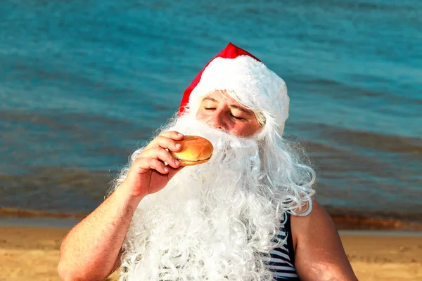 Noel Baba sahilde bir hamburger yemek. 