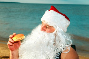 Noel Baba sahilde bir hamburger yemek. 