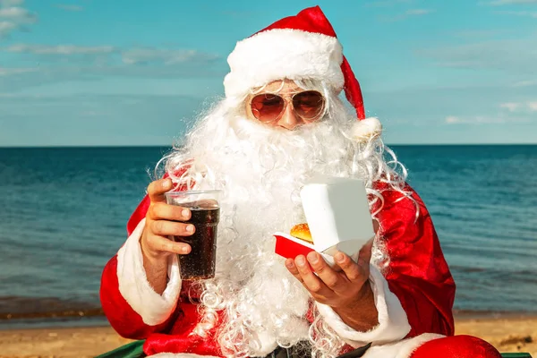 햄버거를 먹고 해변에 산타 클로스. — 스톡 사진
