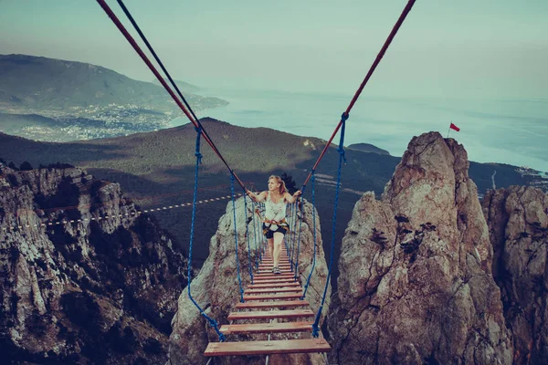 女性奈落の底に吊り橋を歩いています。. — ストック写真
