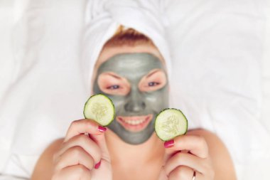 Yüzünde kil maske olan çekici ve komik bir kadın..