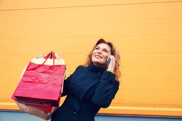 ショッピング バッグ、電話で話していると美しい女性. — ストック写真
