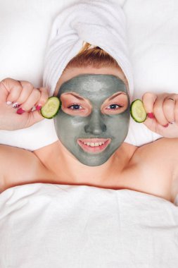 Yüzünde kil maske olan çekici ve komik bir kadın..