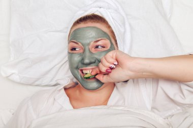 Yüzünde kil maske olan çekici ve komik bir kadın..