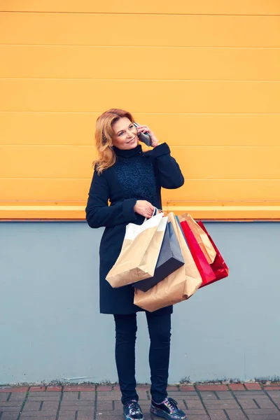 ショッピング バッグ、電話で話していると美しい女性. — ストック写真