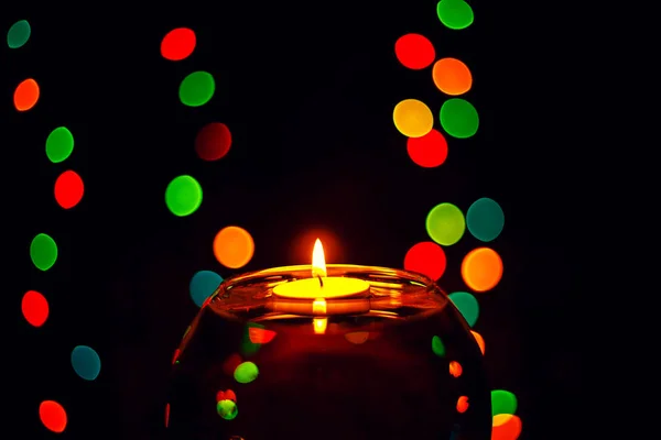 Floating candle and multi-colored garland. — Stock Photo, Image