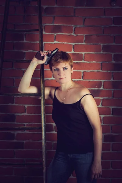 Mujer con el pelo corto sosteniendo un arma en la mano . — Foto de Stock