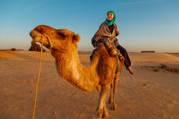 Woman  riding a camel in the Sahara desert.