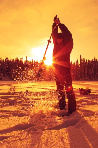 渔夫在冬天晴朗的日子在湖面上钻冰。. — 图库照片