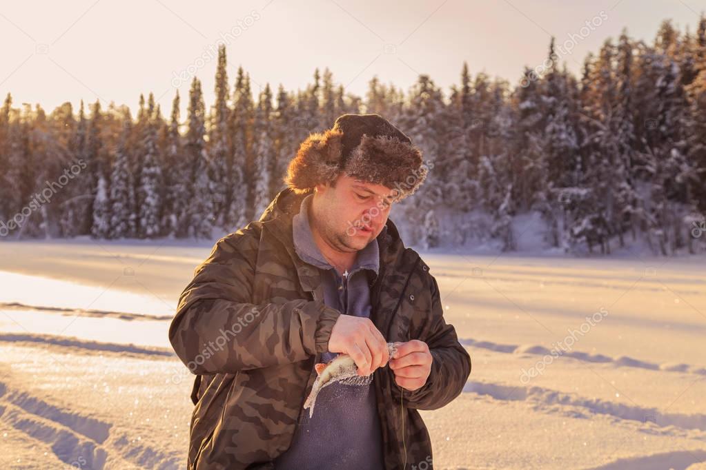 Fisherman on the lake in a winter sunny day. 