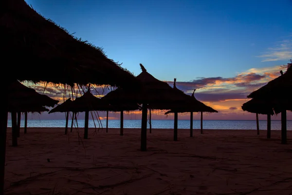 Strohschirme am Strand im Morgengrauen. — Stockfoto