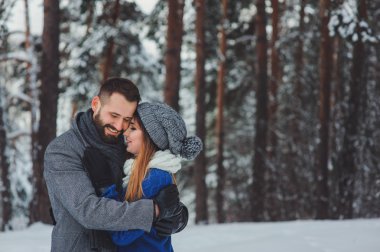 Karlı kış ormanlarında yürüyen, Noel tatilini birlikte geçiren mutlu bir çift. Açık havada mevsimlik aktiviteler. Yaşam stili yakalama.
