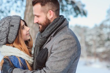 Karlı kış ormanlarında yürüyen, Noel tatilini birlikte geçiren mutlu bir çift. Açık havada mevsimlik aktiviteler. Yaşam stili yakalama.