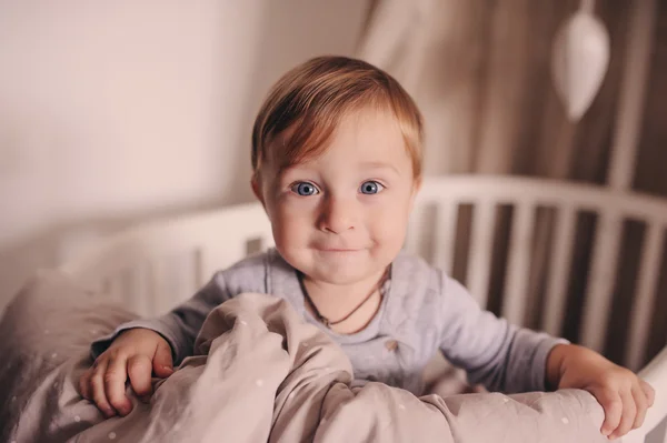 Aranyos boldog kisfiú ébren ágyában reggel és játszik. Őszinte elfog valós belső — Stock Fotó