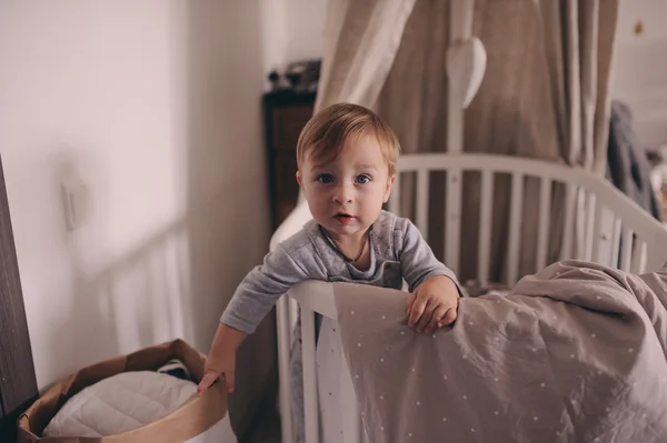 Cute happy baby boy awake in his bed in the morning and playing. Candid capture in real life interior — Stock Photo, Image