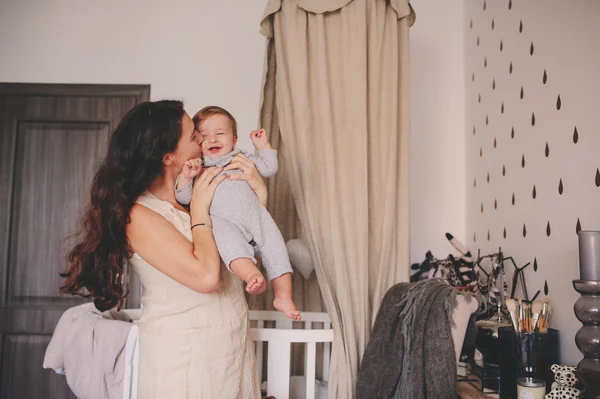Heureux mère et bébé fils jouer ensemble à la maison, maman tenant et embrassant son garçon de 11 mois, mode de vie confortable — Photo