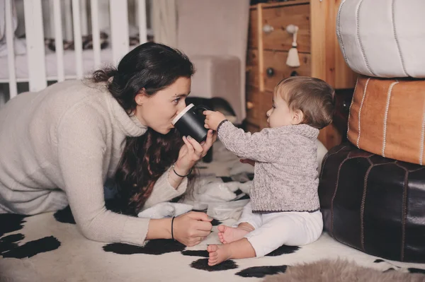 Moeder en baby zoon thuis samenspelen. Het onderwijzen van baby uit de Beker drinken. Gelukkige familie levensstijl concept — Stockfoto