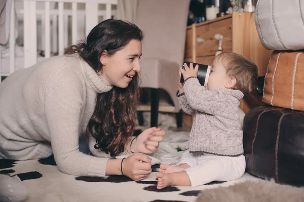 Moeder en baby zoon thuis samenspelen. Het onderwijzen van baby uit de Beker drinken. Gelukkige familie levensstijl concept — Stockfoto