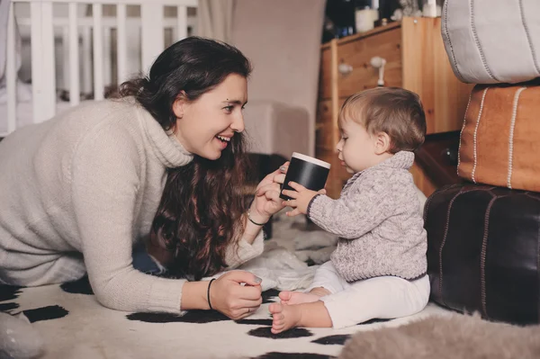 Anya és a baba fiú együtt játszanak otthon. Tanítás baba inni a poharat. Boldog családi életmód fogalma — Stock Fotó