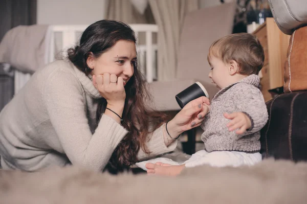 Mère et bébé fils jouent ensemble à la maison. Apprendre au bébé à boire dans une tasse. Concept de vie familiale heureuse — Photo